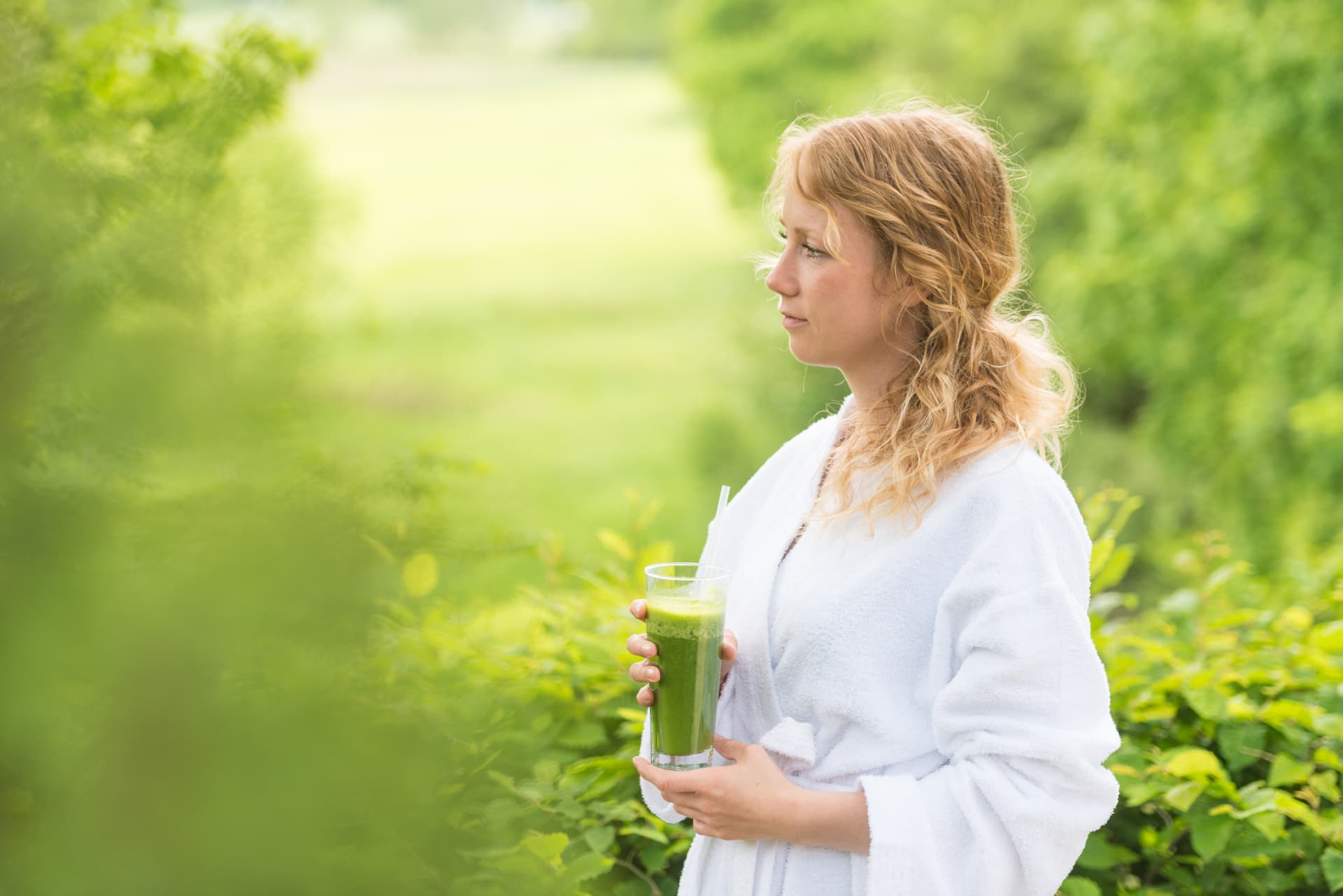 Frau im Bademantel mit Gemüsesaft