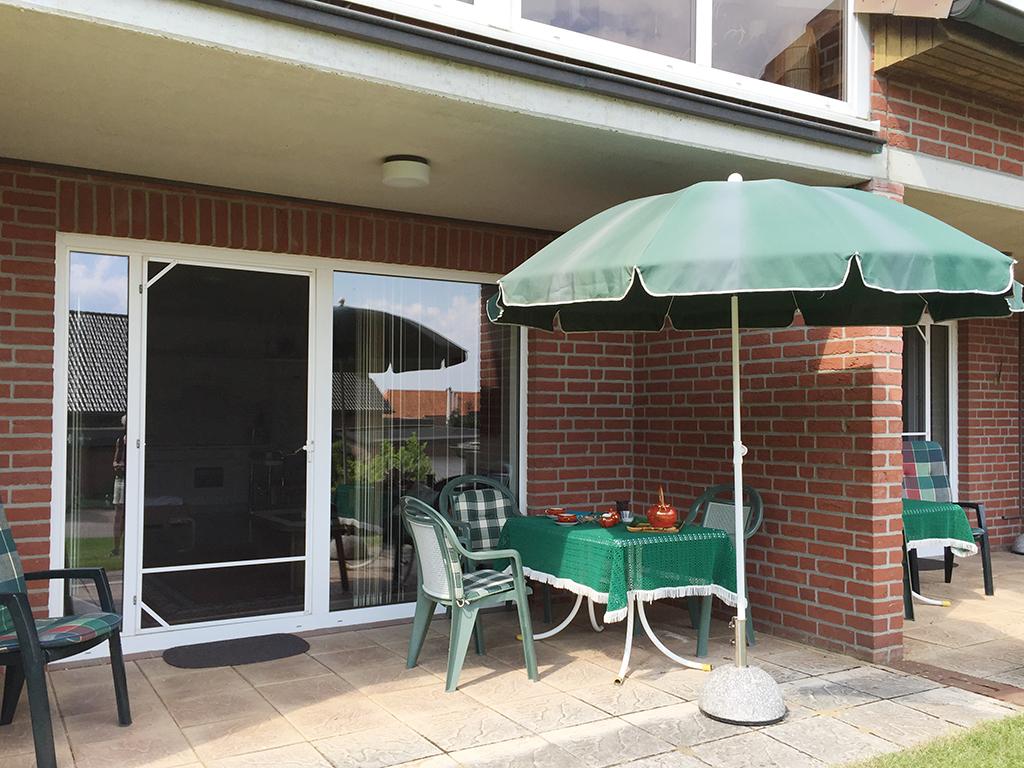 sonnige Terrasse mit Bestuhlung und Schirm