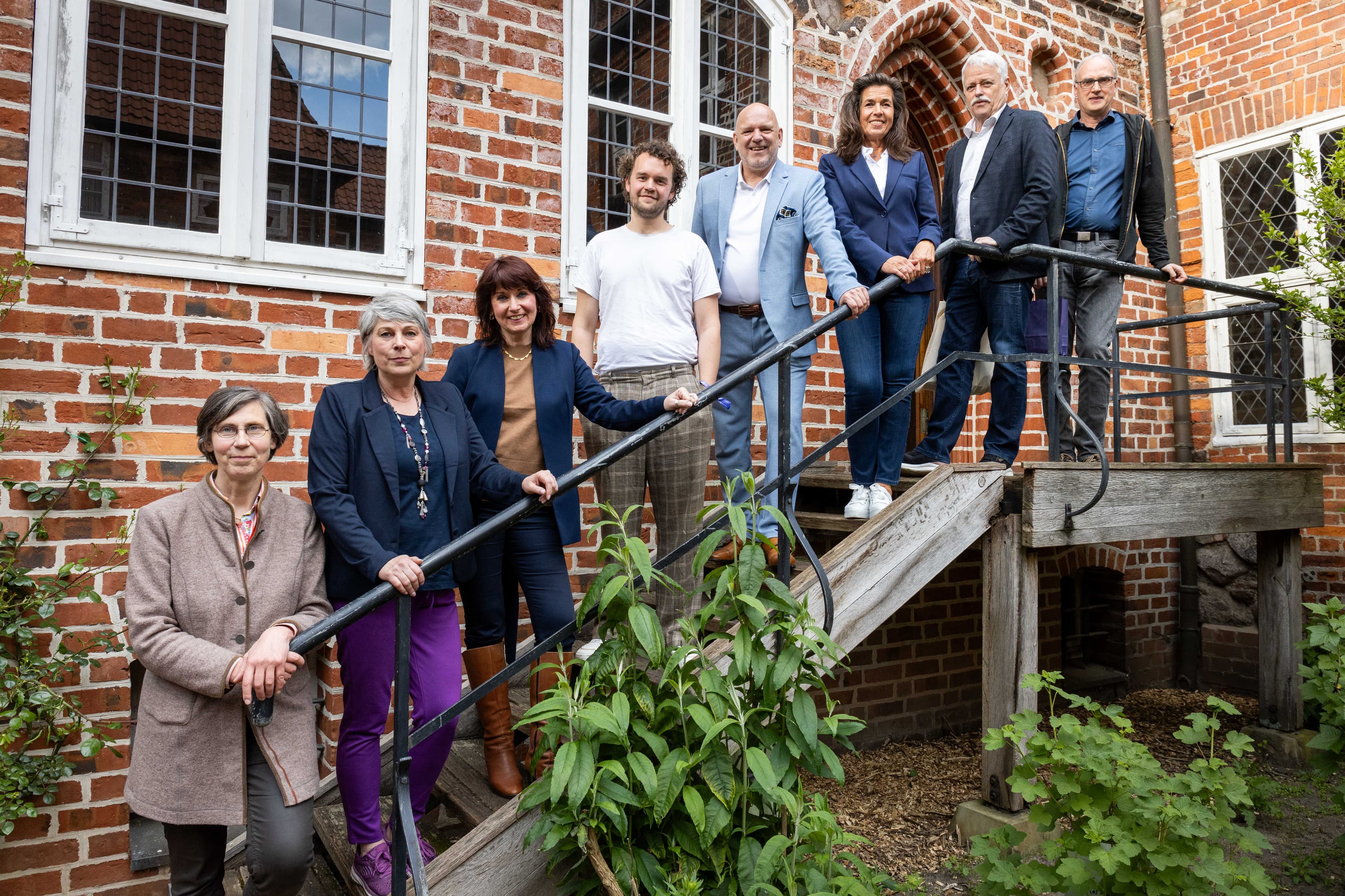 eine gruppe menschen steht auf einer treppe. es sind männer und frauen.