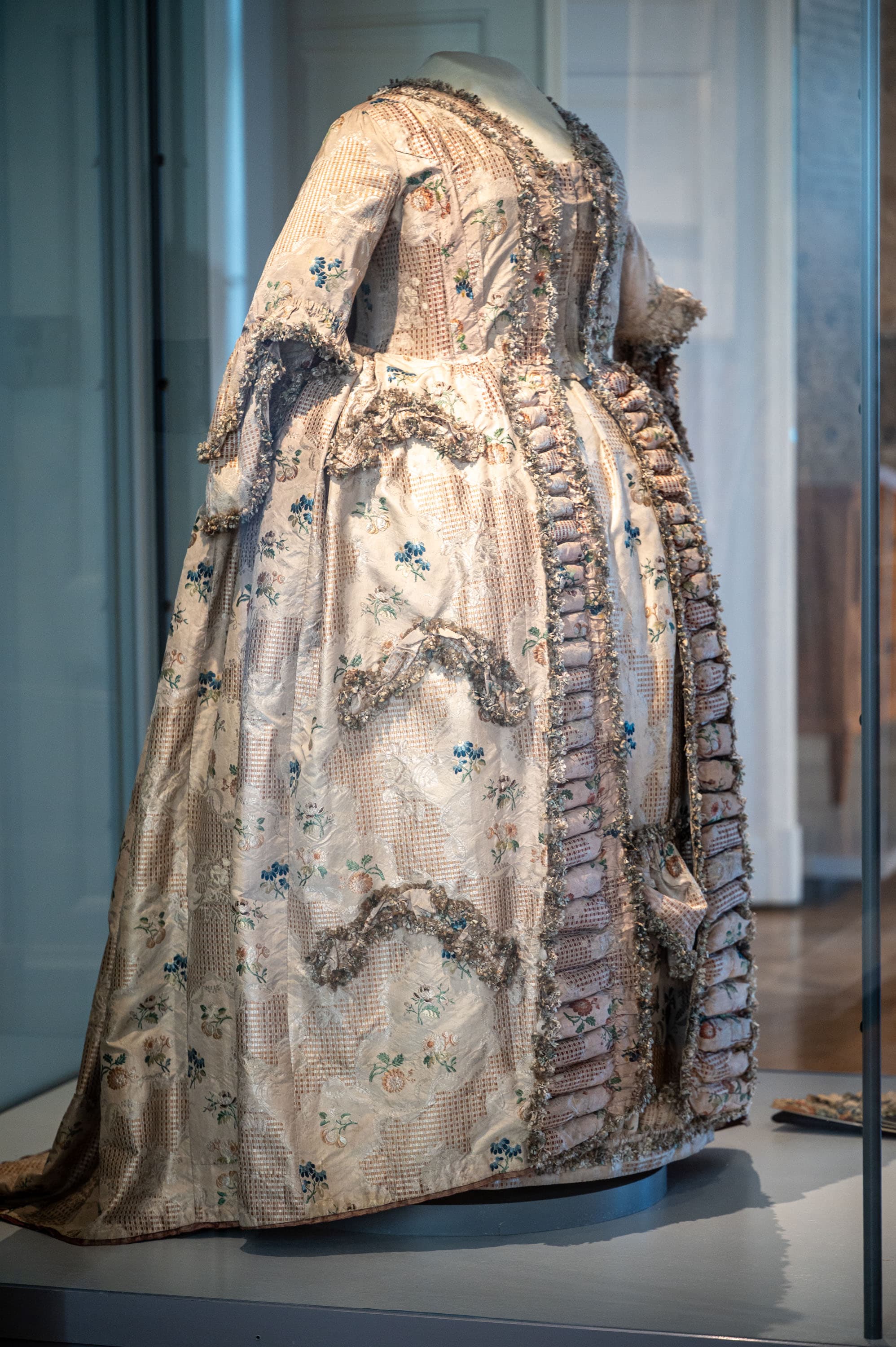 Prunkvolles, helles Barockkleid mit floralem Muster und Rüschen im Residenzmuseum Schloss Celle.