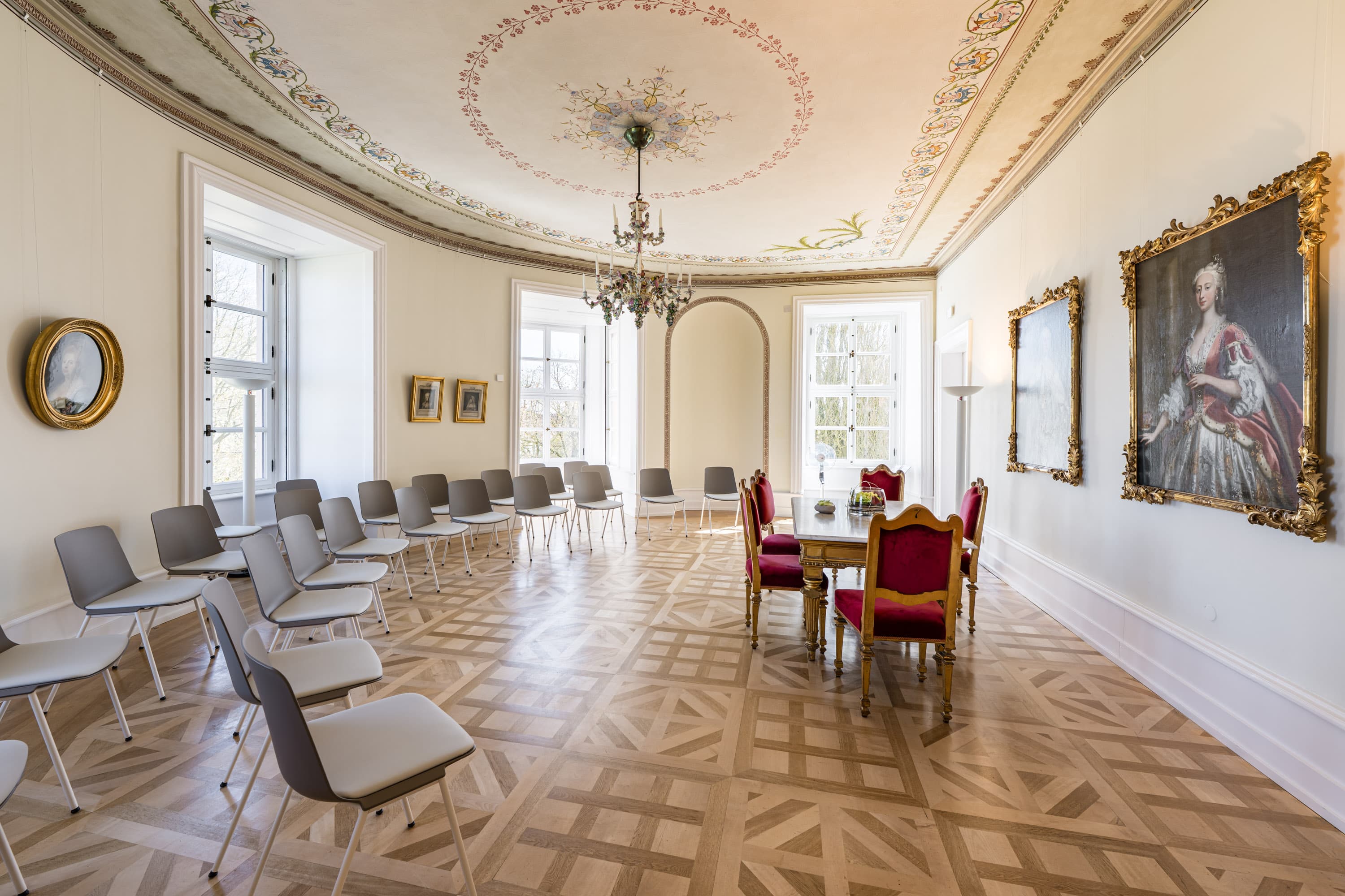 Heller, festlicher Saal im Schloss Celle mit Parkett, Deckengemälde und Bestuhlung für eine Trauung.