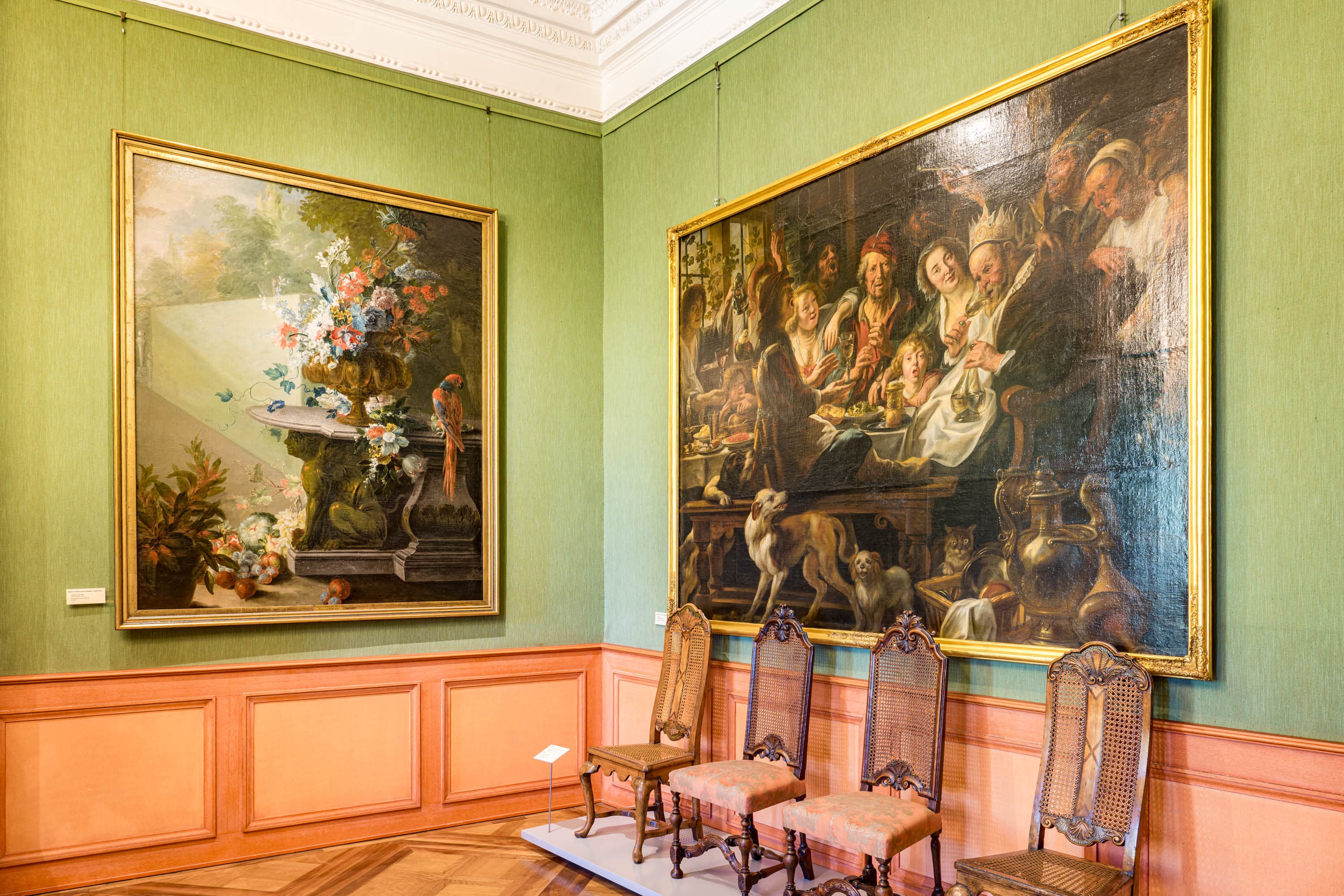 Zwei große Barockgemälde in Goldrahmen an der grünen Wand eines Raums im Residenzmuseum Celle.