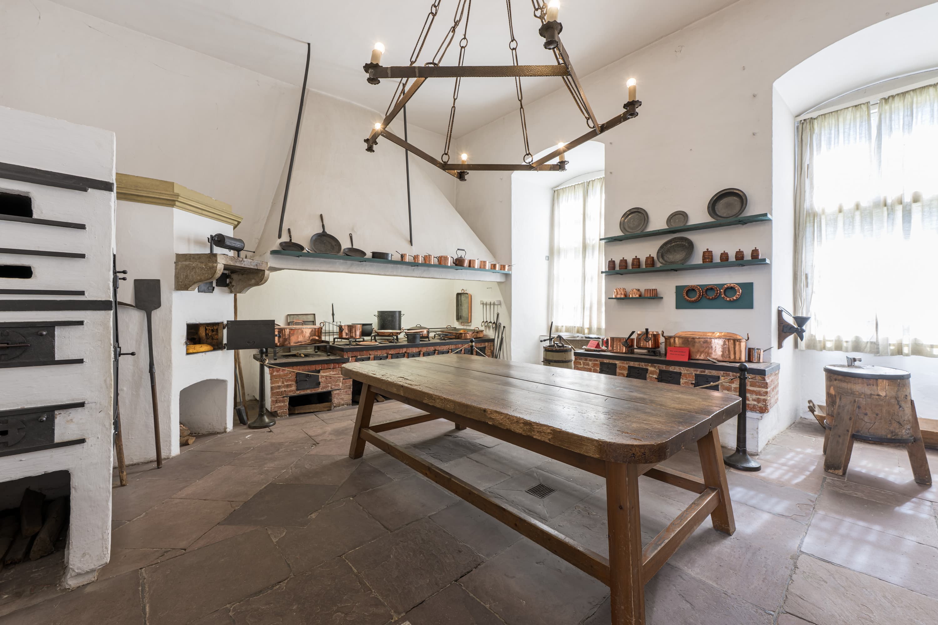 Die historische Schlossküche im Residenzmuseum Celle mit Holztisch, gemauertem Herd und Kupfertöpfen.